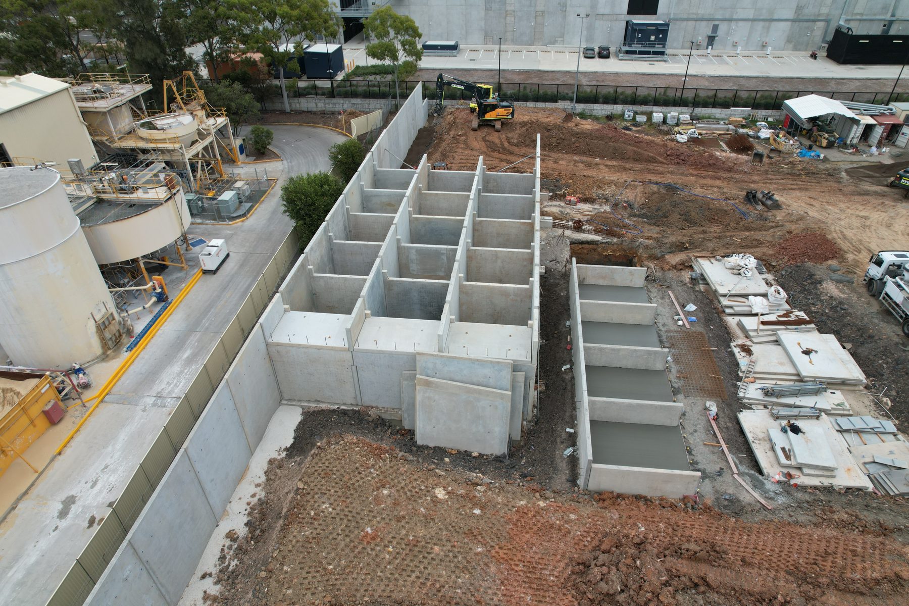 Aerial view of precast concrete bin walls under construction beside an operating plant